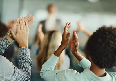 Back view of people clapping for a person standing in the front.